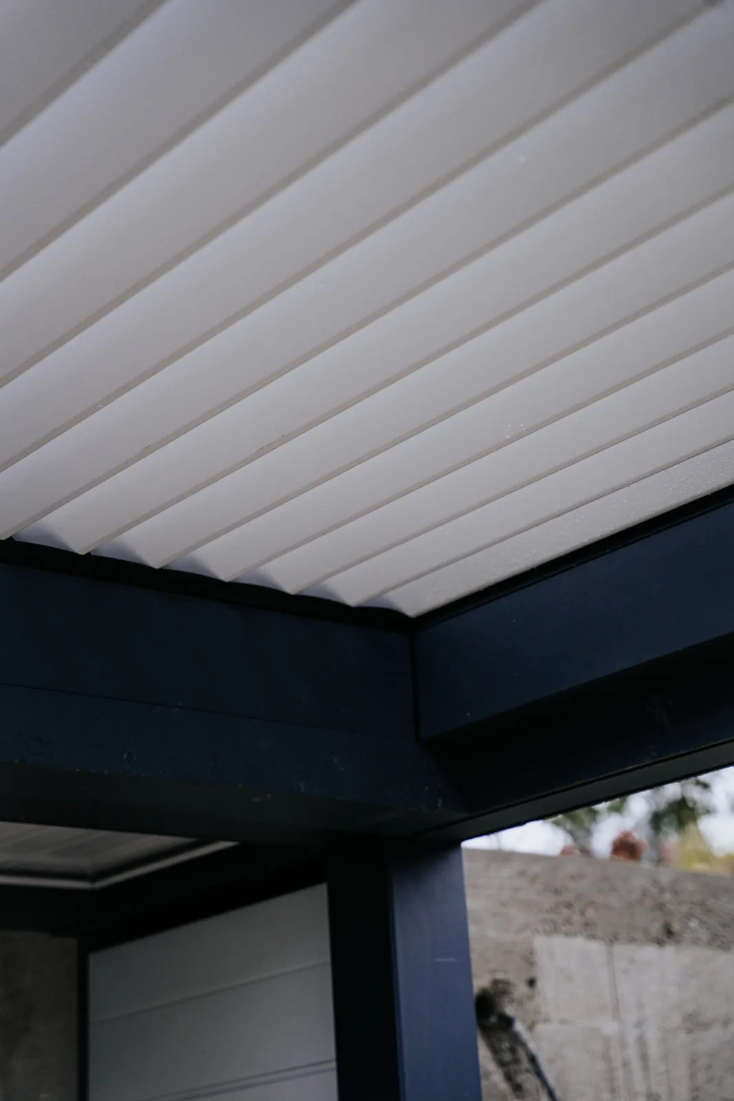 Lamele albe închise sub cadrul antracit al unei pergole bio-retractabile HEXANN