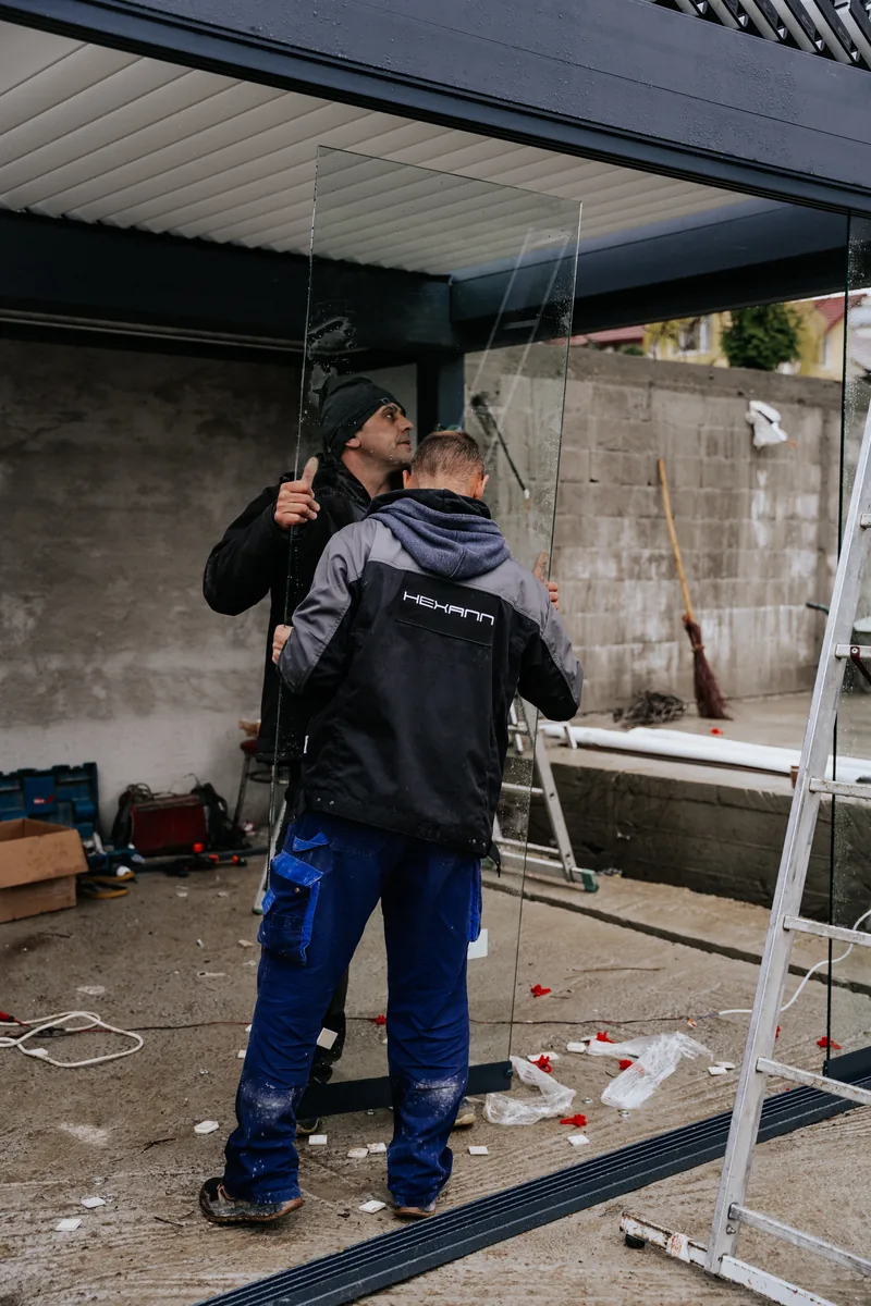 Doi montatori HEXANN lucrează sub structura pergolei bio-retractabile din Cluj